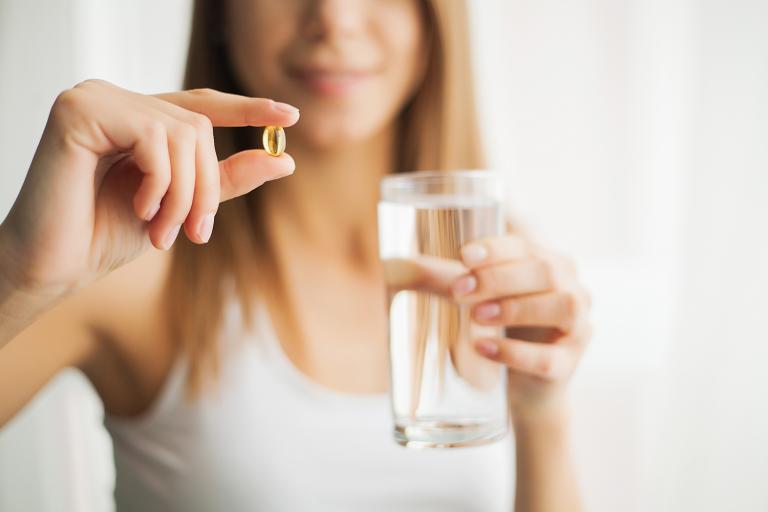 a calm and happy woman taking a capsule of CBD